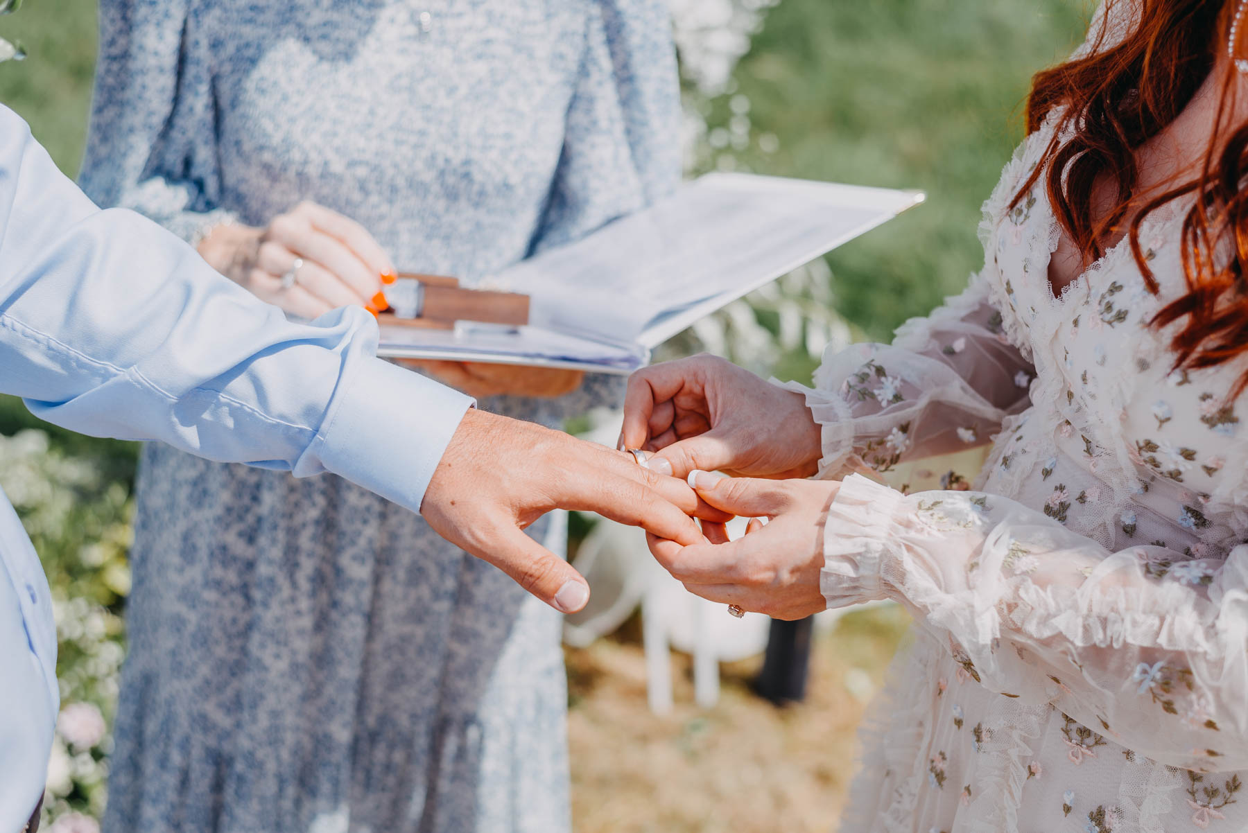 The bride puts a wedding ring on the groom's finger during the handfasting ceremony