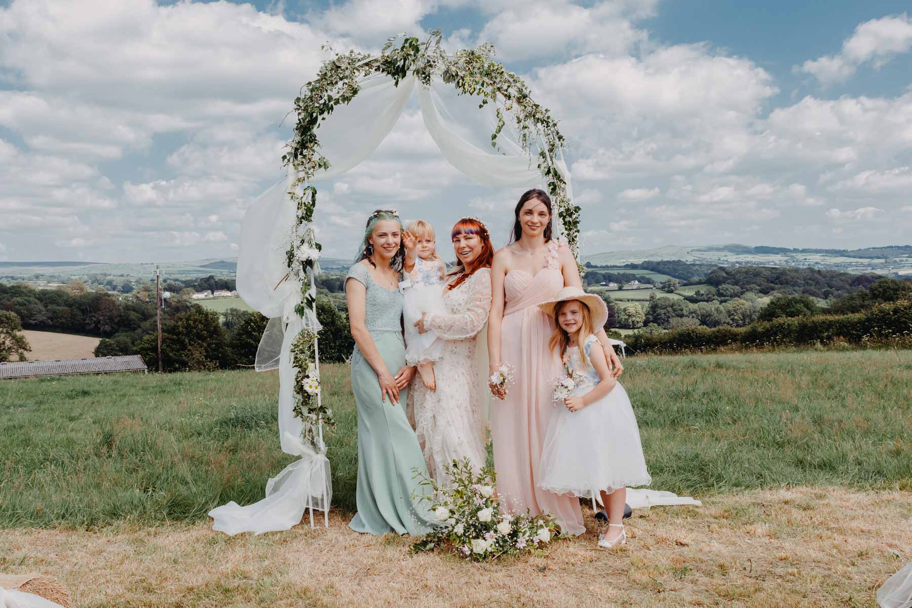 The bride and two bridesmaids and two small girls in the group photo after the handfasting ceremony