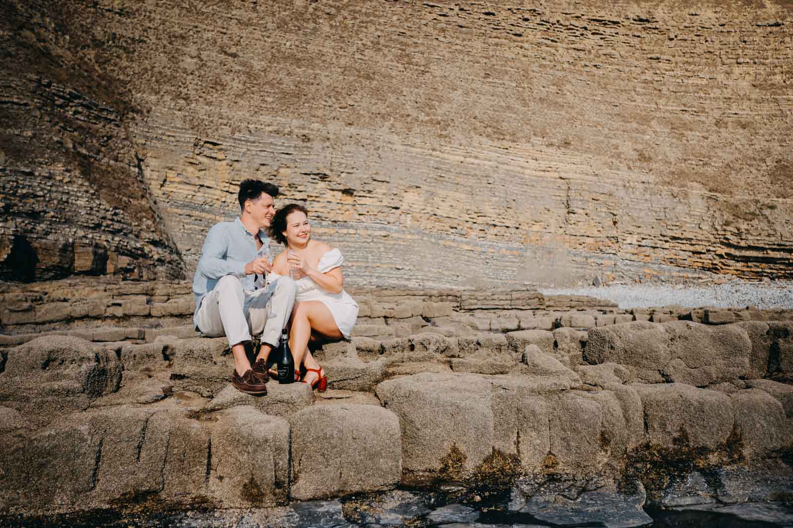 Couple sitting on the rock during the engagement photoshoot Wales