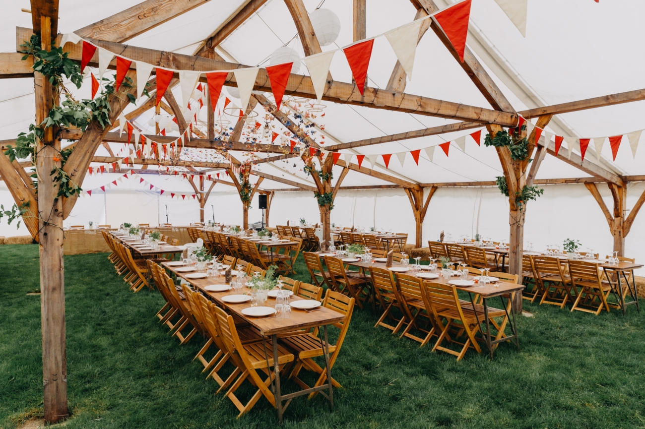 Festival wedding reception setup with long wooden tables and colourful bunting at Splotts Moor in Glastonbury.