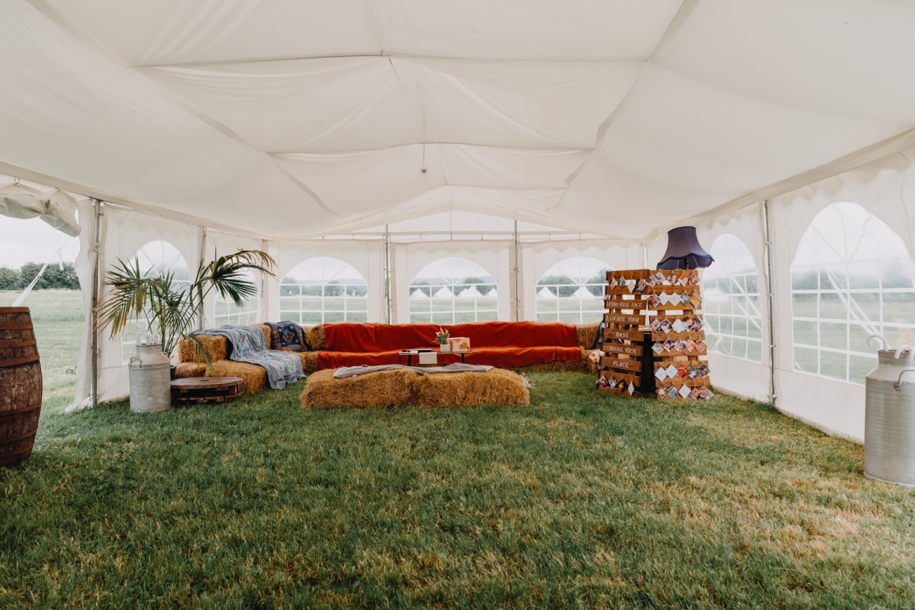 Chill-out area with hay bale seating and a seating chart in a marquee at Splotts Moor in Glastonbury.