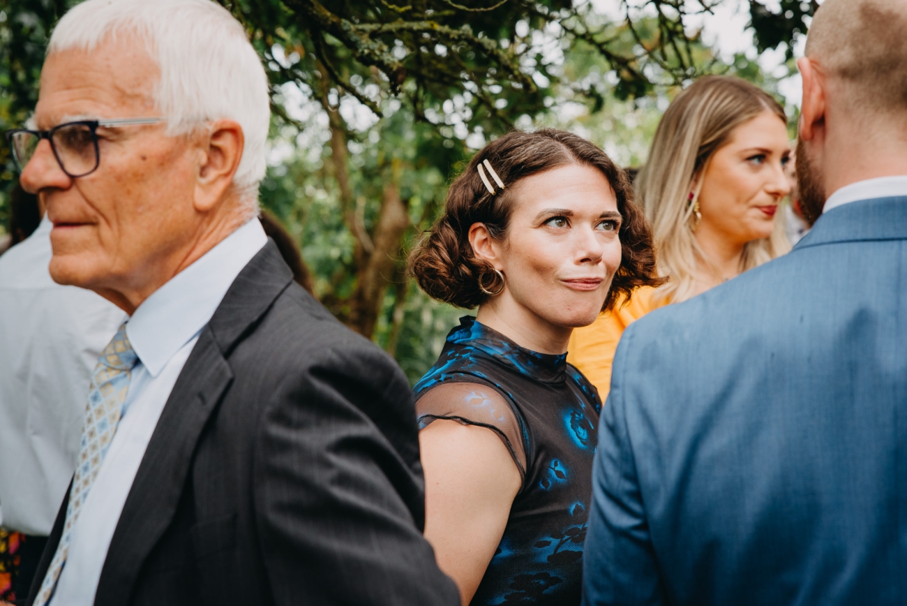 Wedding guests sharing candid expressions during a festival-themed celebration at Splotts Moor in Glastonbury.