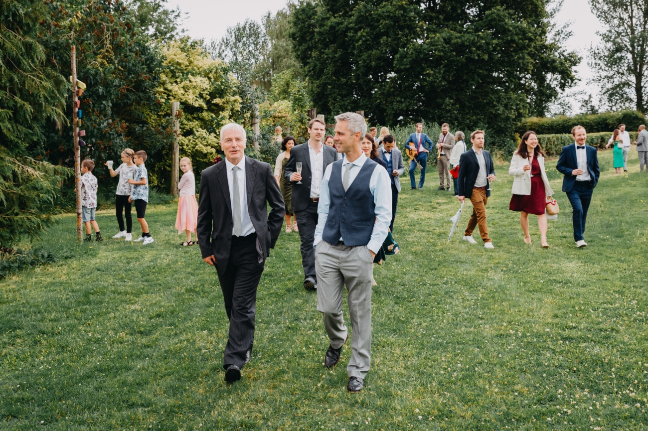 Wedding guests casually strolling through the outdoor setting of a festival-themed wedding at Splotts Moor in Glastonbury.