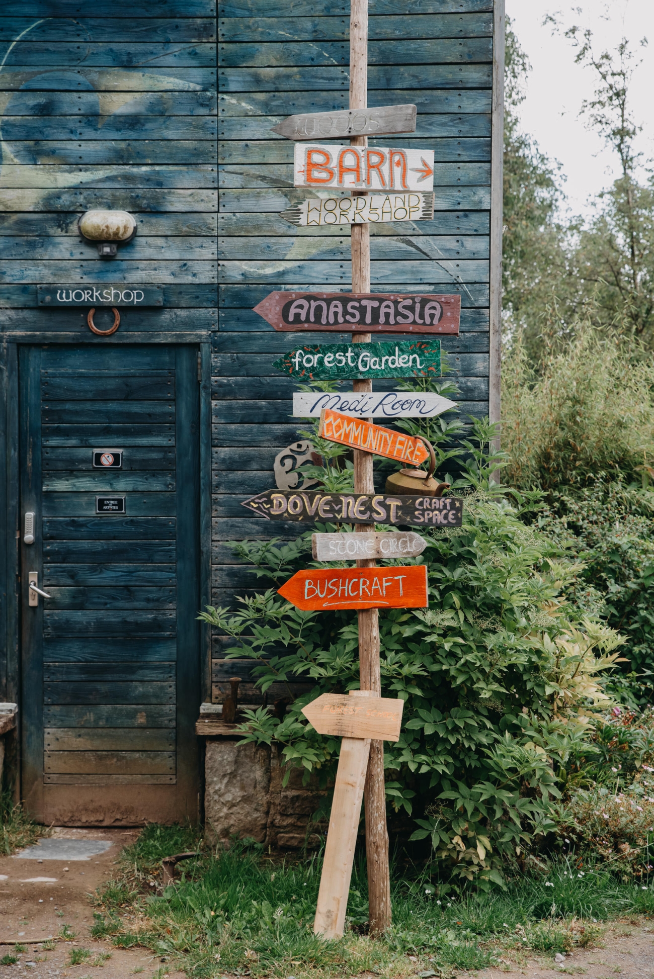 Rustic wooden signpost with hand-painted directional signs for various locations at Coed Weddings, a countryside wedding venue near Cowbridge, Wales.