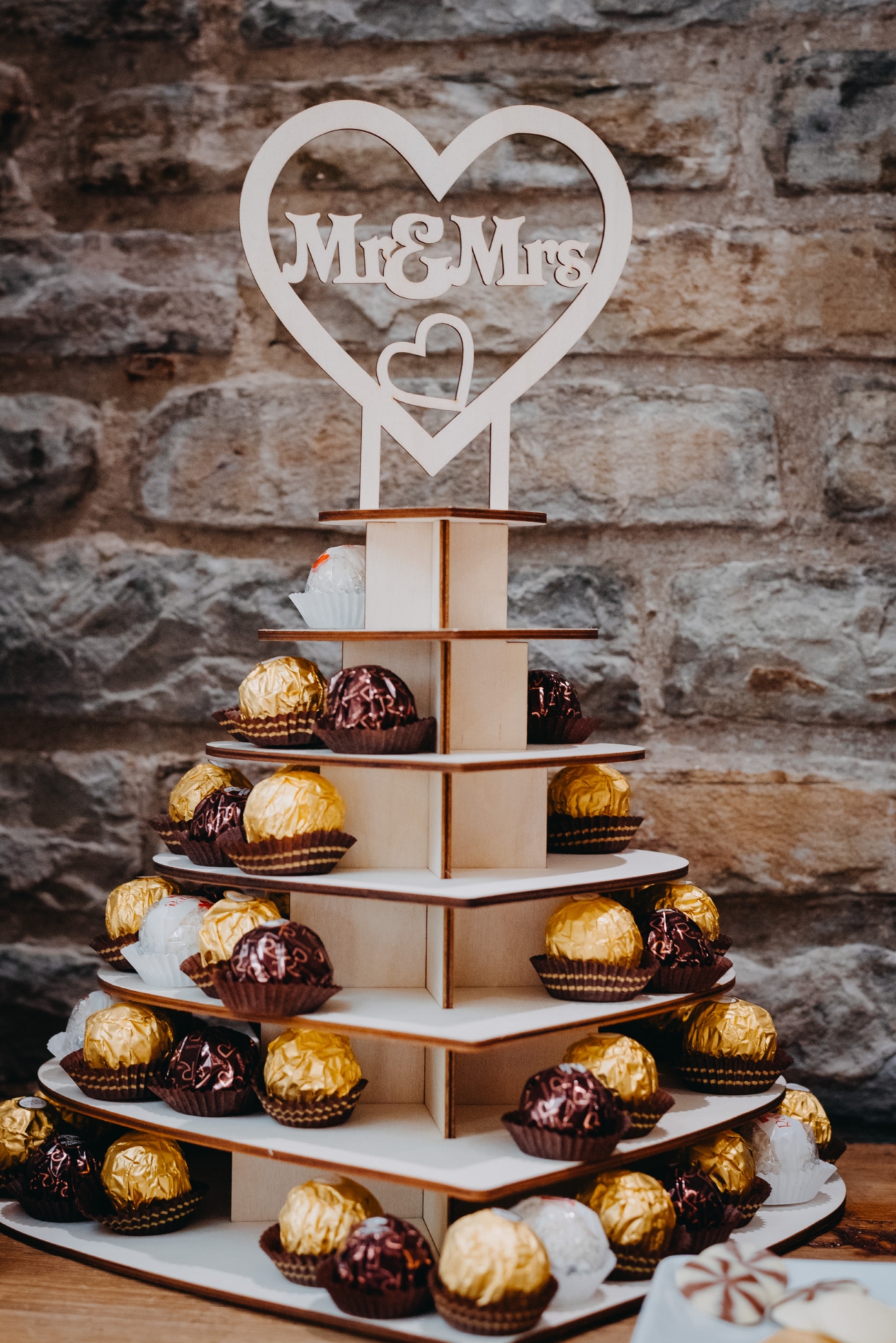 A close-up of a wooden wedding display stand at Lanelay Hall in Pontyclun, featuring Ferrero Rocher chocolates with a 'Mr & Mrs' heart-shaped topper.