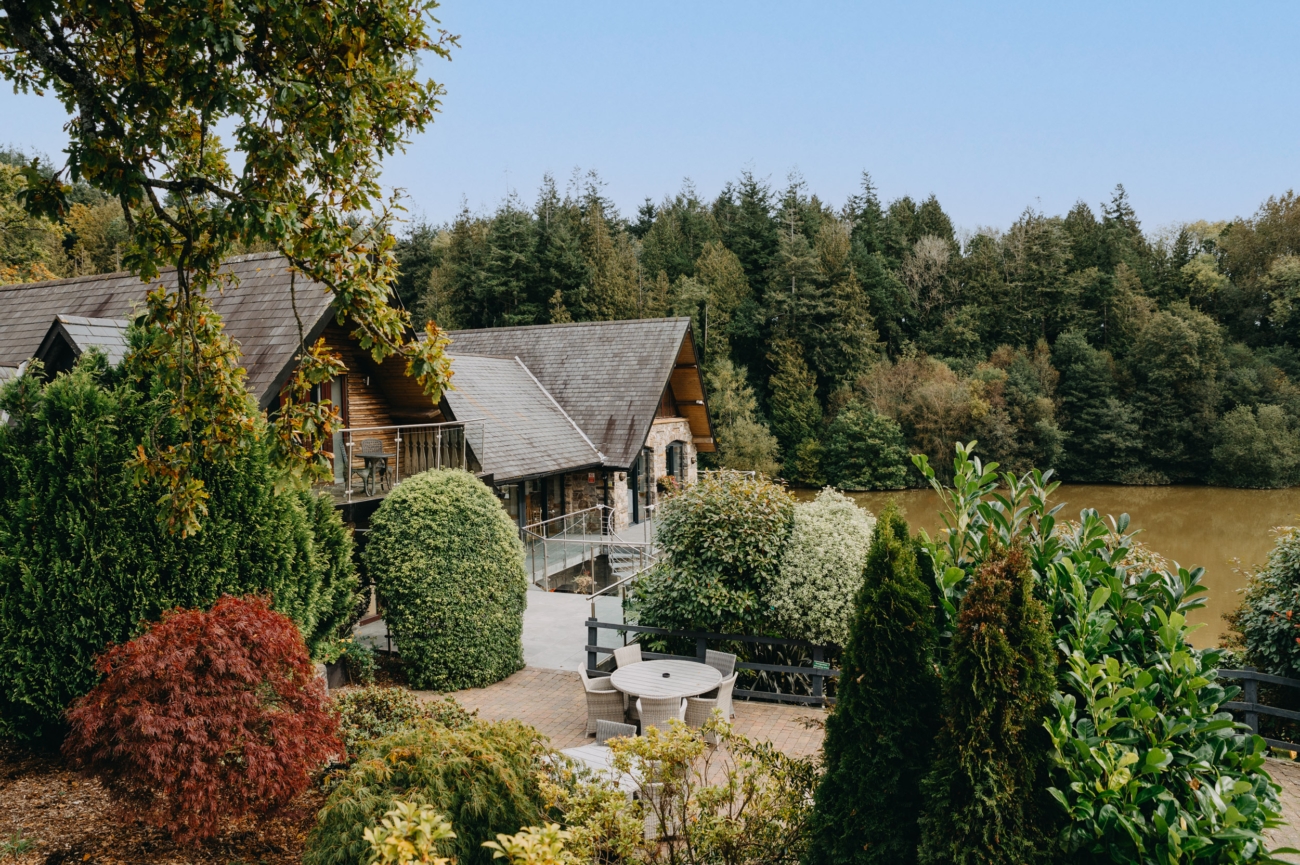 Charming lodge at Canada Lodge & Lake surrounded by lush greenery, offering a romantic and secluded wedding venue with stunning views over the lake.