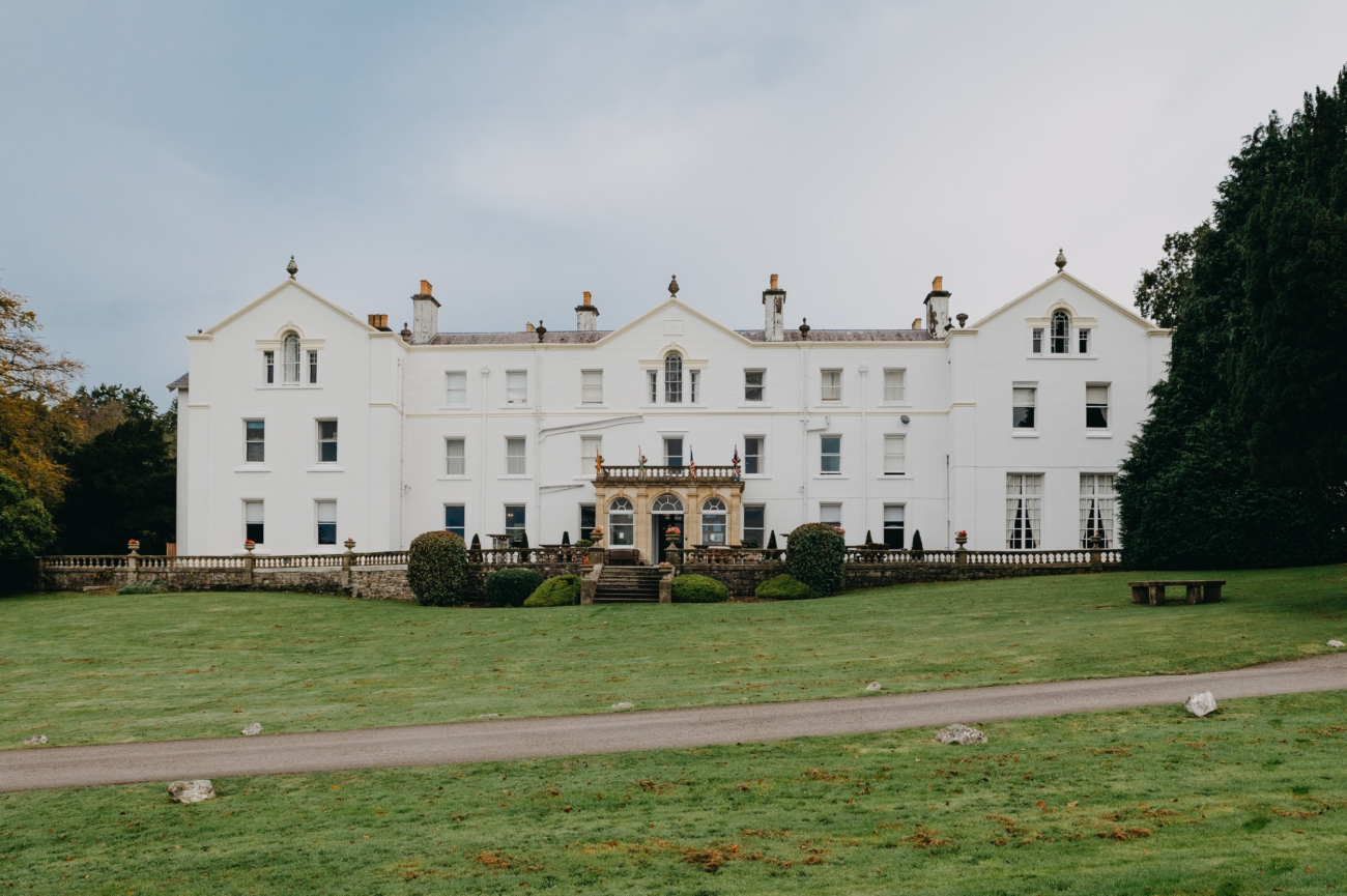 A front view of Court Colman Manor, a stunning wedding venue near Bridgend, featuring its grand white façade and lush green surroundings