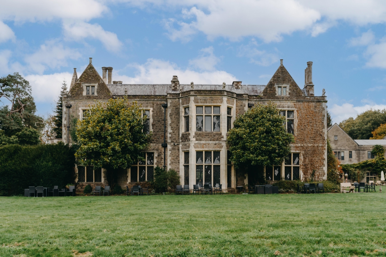 Front view of Miskin Manor Hotel, a historic stone building surrounded by lush greenery, offering a serene and elegant setting for weddings and events.