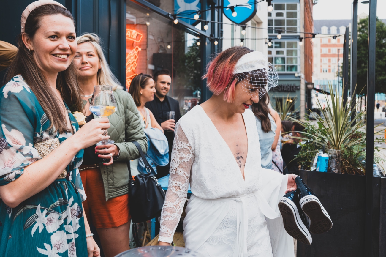 Bride holding her shoes during a relaxed wedding reception.