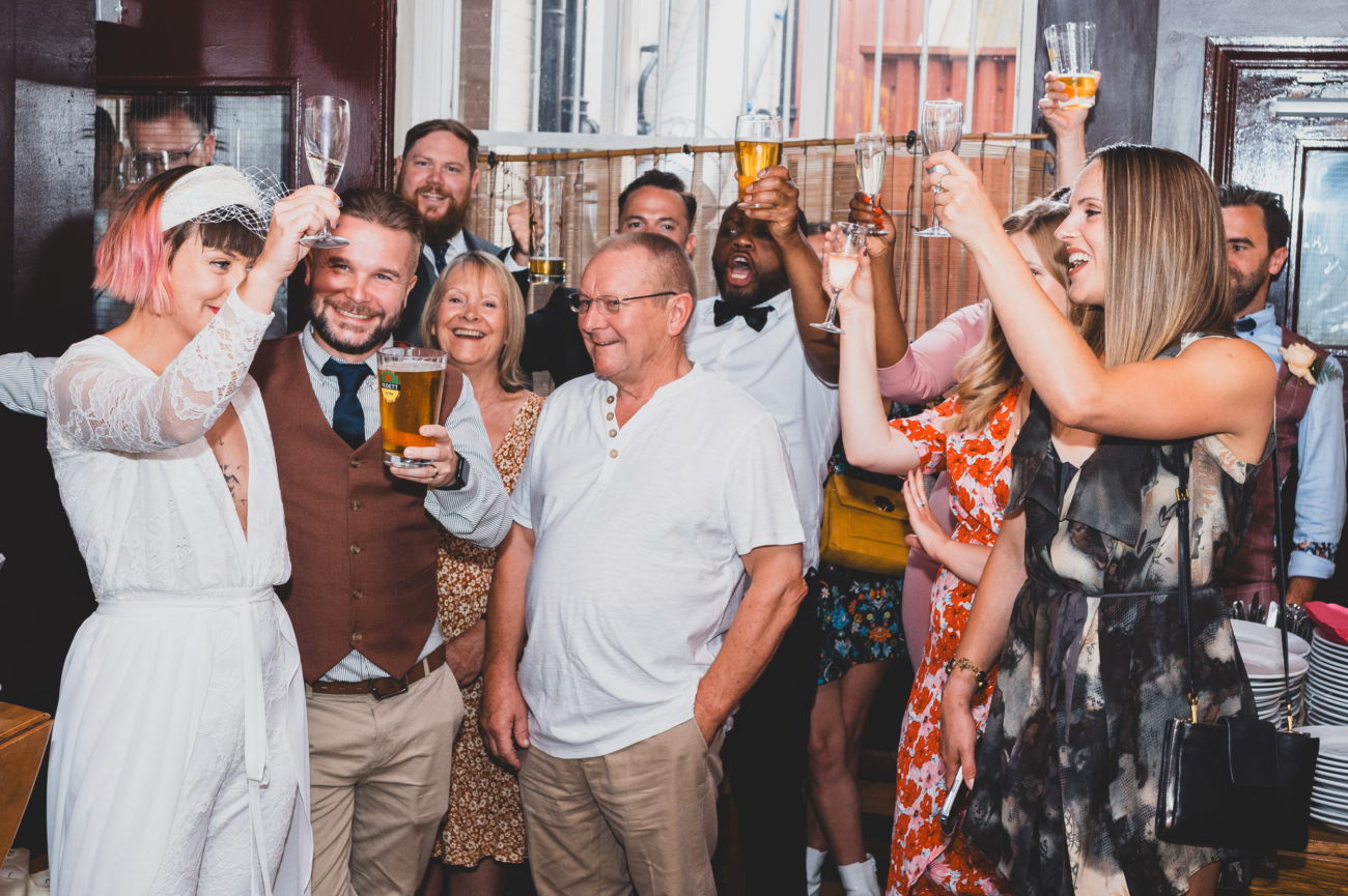 Bride and groom raising a toast with guests, showcasing authentic wedding photography.