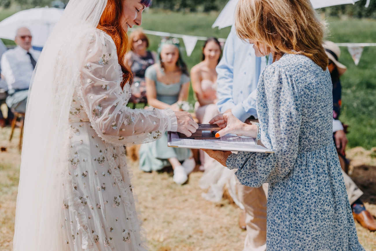 Bride taking the wedding ring from a box during an outdoor ceremony, showcasing authentic wedding photography.
