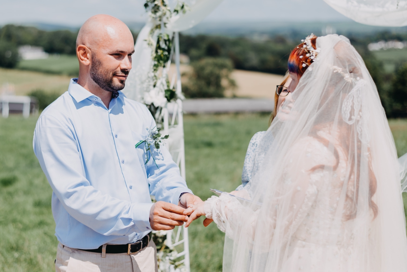 Groom placing a ring on the bride’s finger, showcasing real wedding moments.