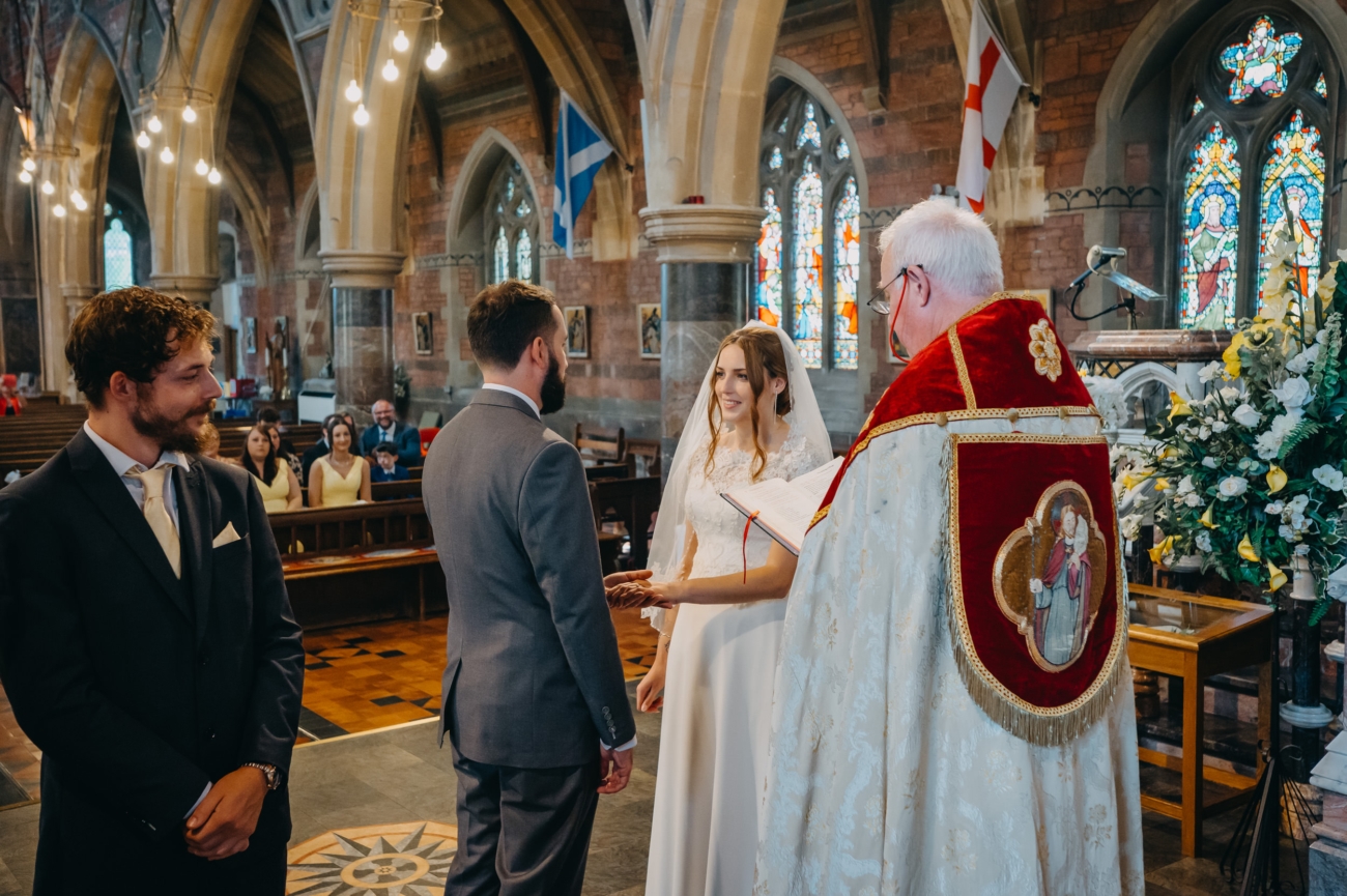 Bride and groom exchange vows during their wedding ceremony at All Saints Church Babbacombe, a stunning wedding venue in Devon.