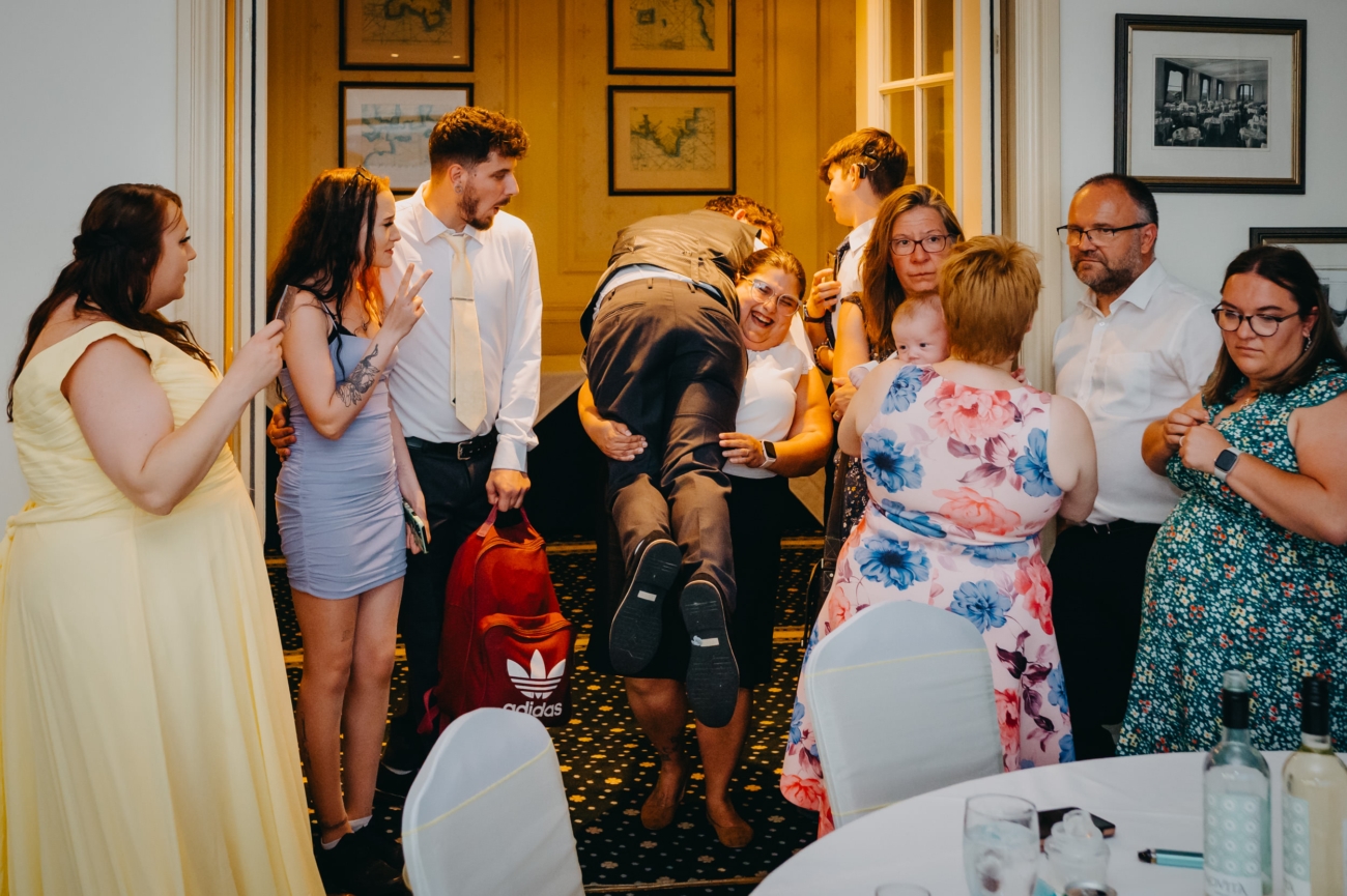 Wedding guests laughing and having fun as a woman lifts a man playfully at the reception in The Imperial Hotel Torquay.