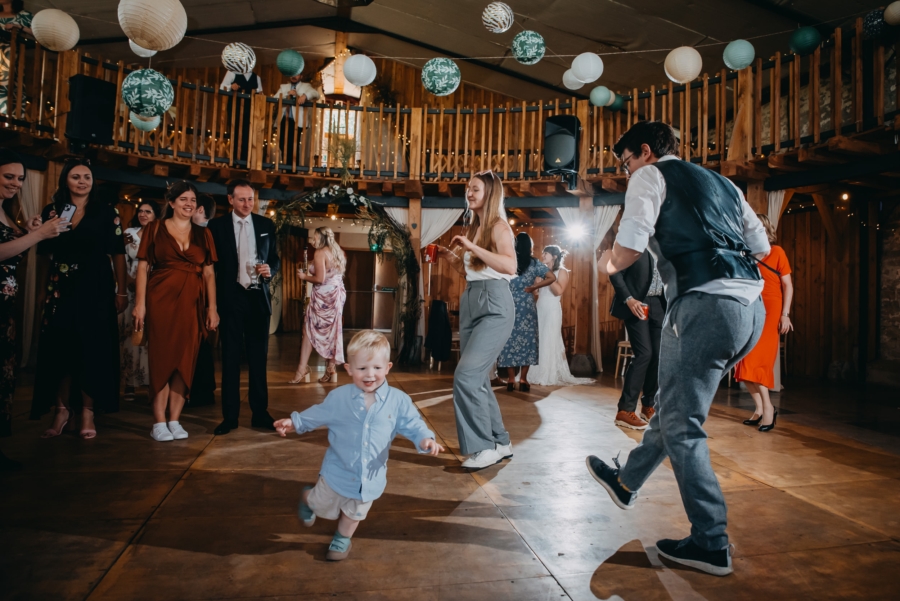 Young child dancing joyfully at a wedding reception surrounded by guests