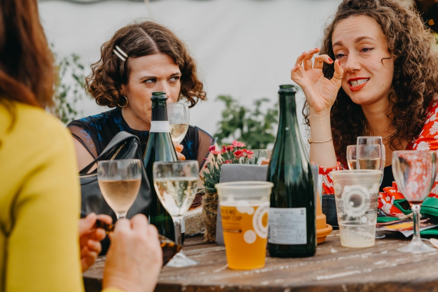 Natural wedding guest photo of women chatting over drinks – candid moment at outdoor reception