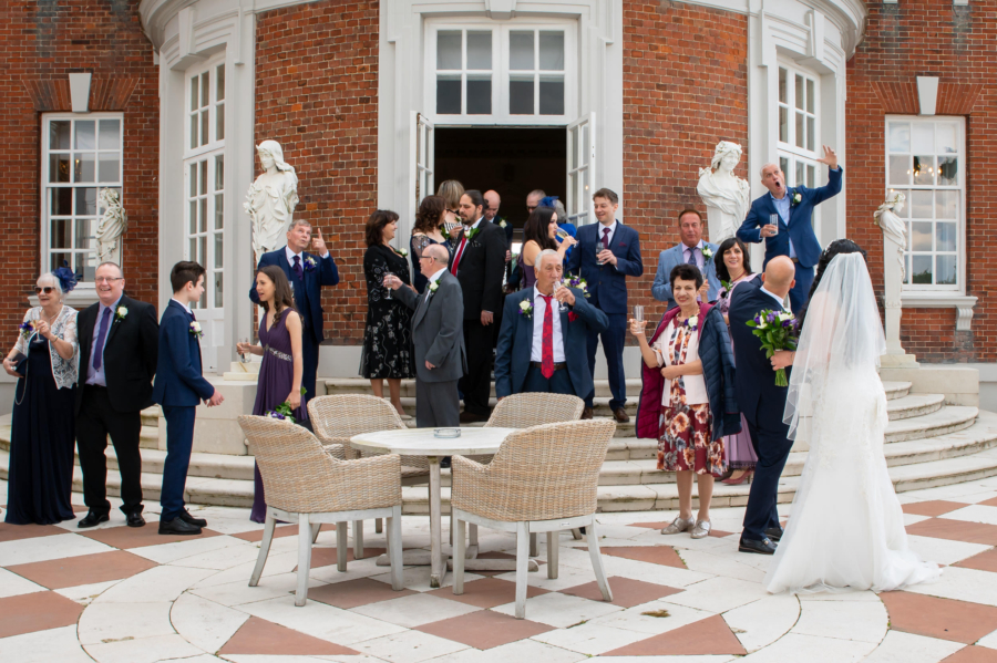 Relaxed wedding guest photo on mansion steps with bride in the foreground