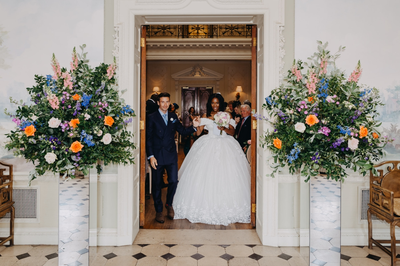Bride and groom leaving floral wedding ceremony in a classic white dress