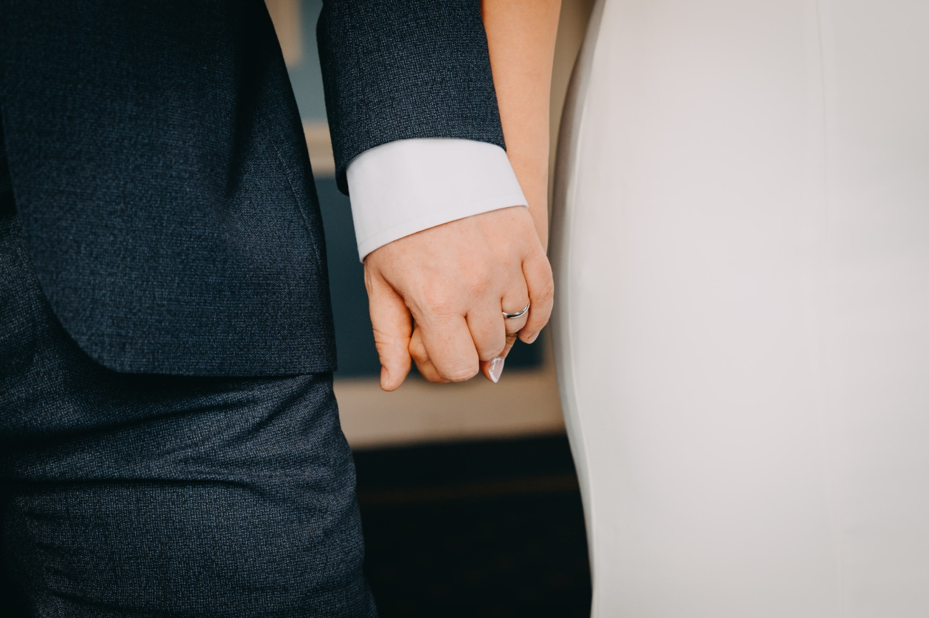 Wedding couple holding hands on their special day — documentary wedding photographer captures timeless and intimate moment.