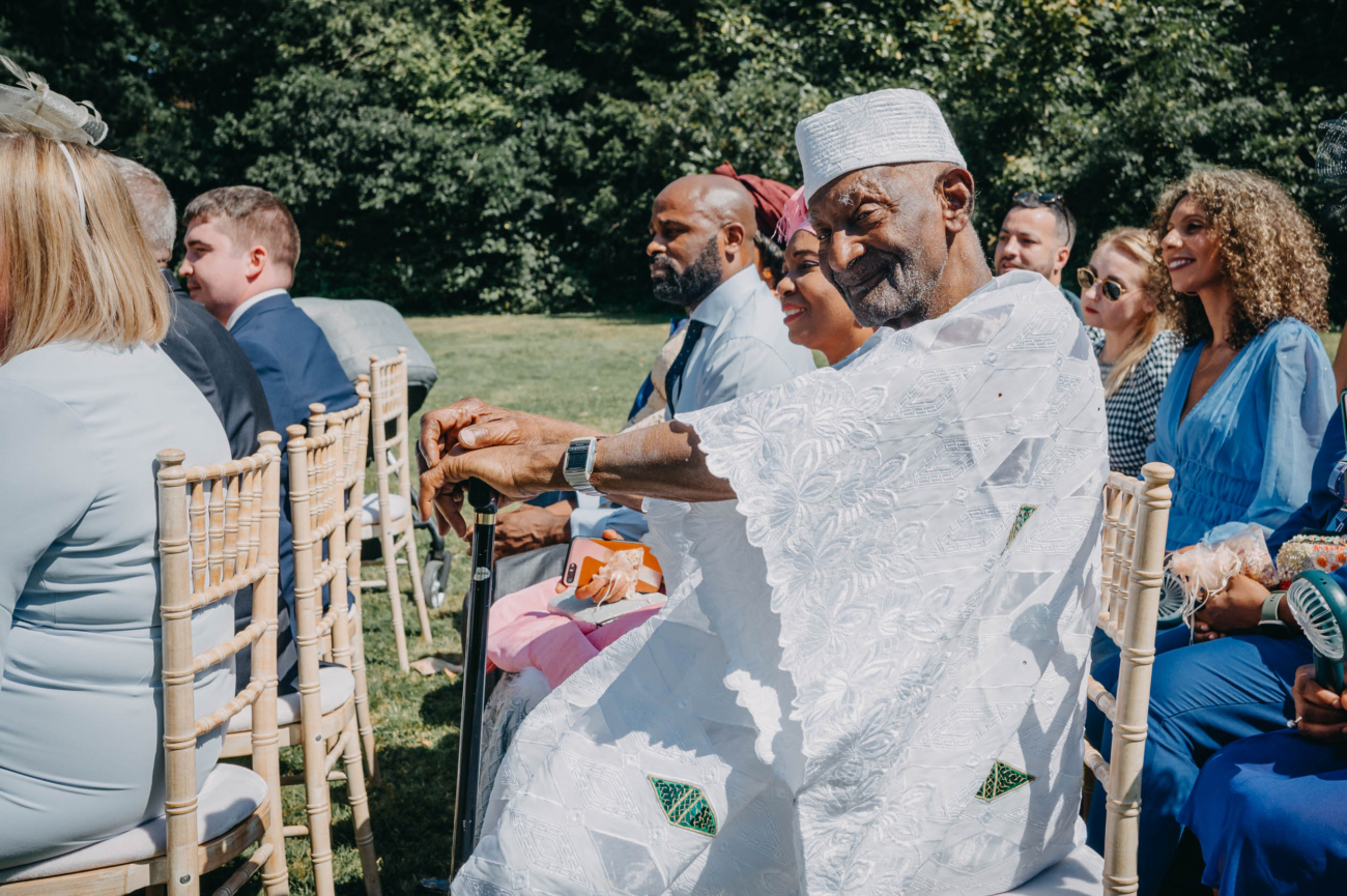 Portrait of an elderly wedding guest with a gentle smile, seated among friends at Glansevin Mansion.