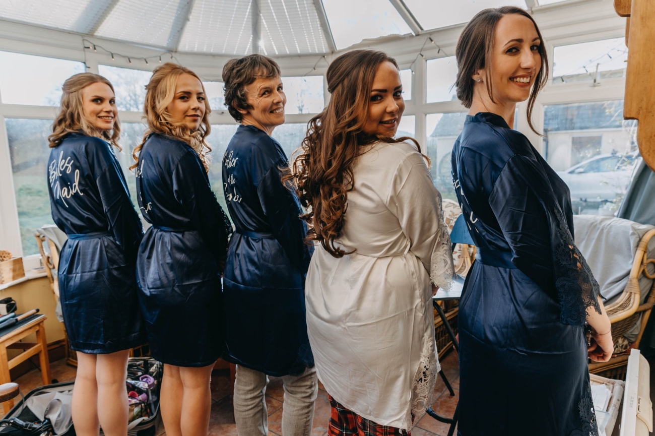 Bride, bridesmaids and mother smiling during relaxed wedding morning in Myddfai