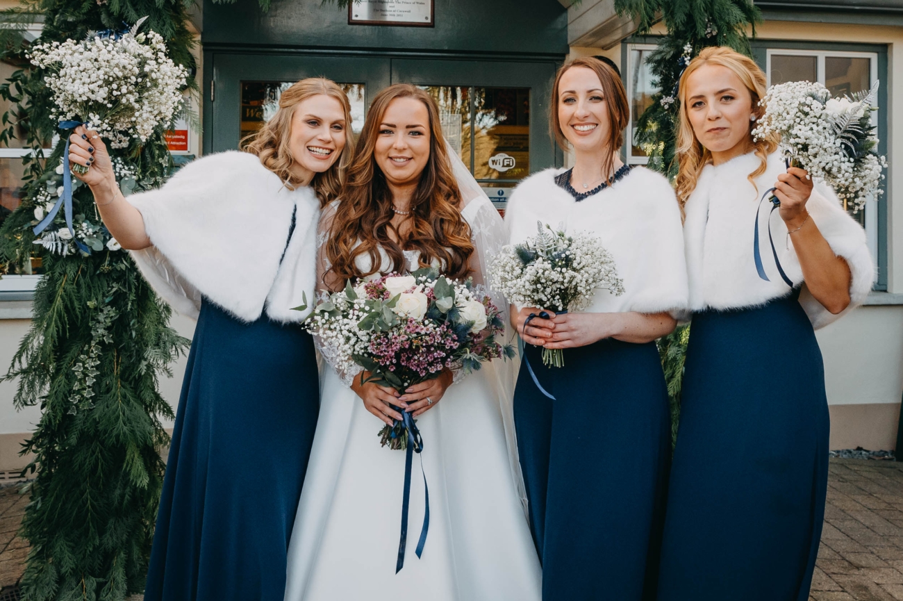 Bride and bridesmaids posing outside Myddfai Community Hall after a winter wedding ceremony in Wales