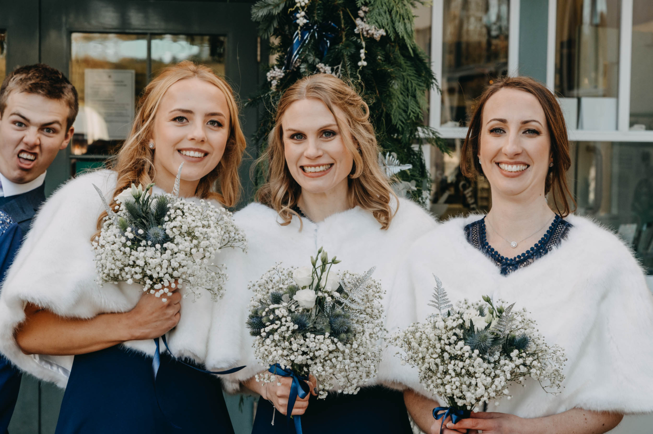 Bridesmaids posing after the wedding ceremony in Myddfai – with a surprise photobomb from a guest in the background