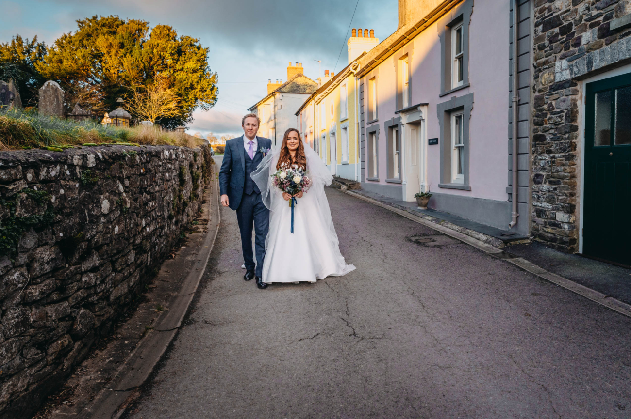 Bride and groom walking through the village of Myddfai at sunset – romantic portrait after their wedding ceremony