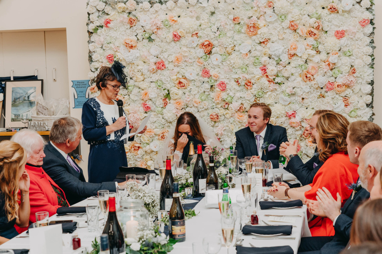 Bride wiping away tears as her mother gives an emotional wedding speech at Myddfai Community Hall