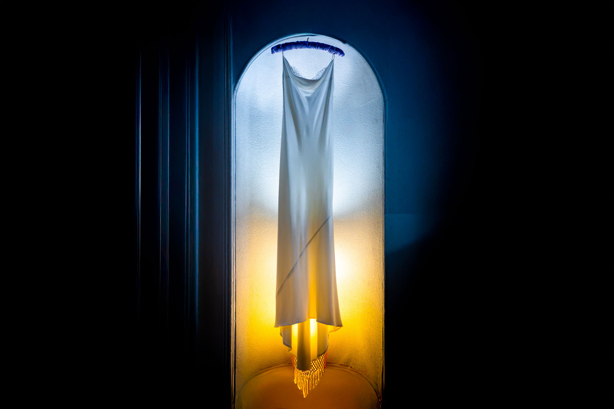 White wedding dress illuminated by contrasting blue and amber light, exploring how lighting changes colour perception.