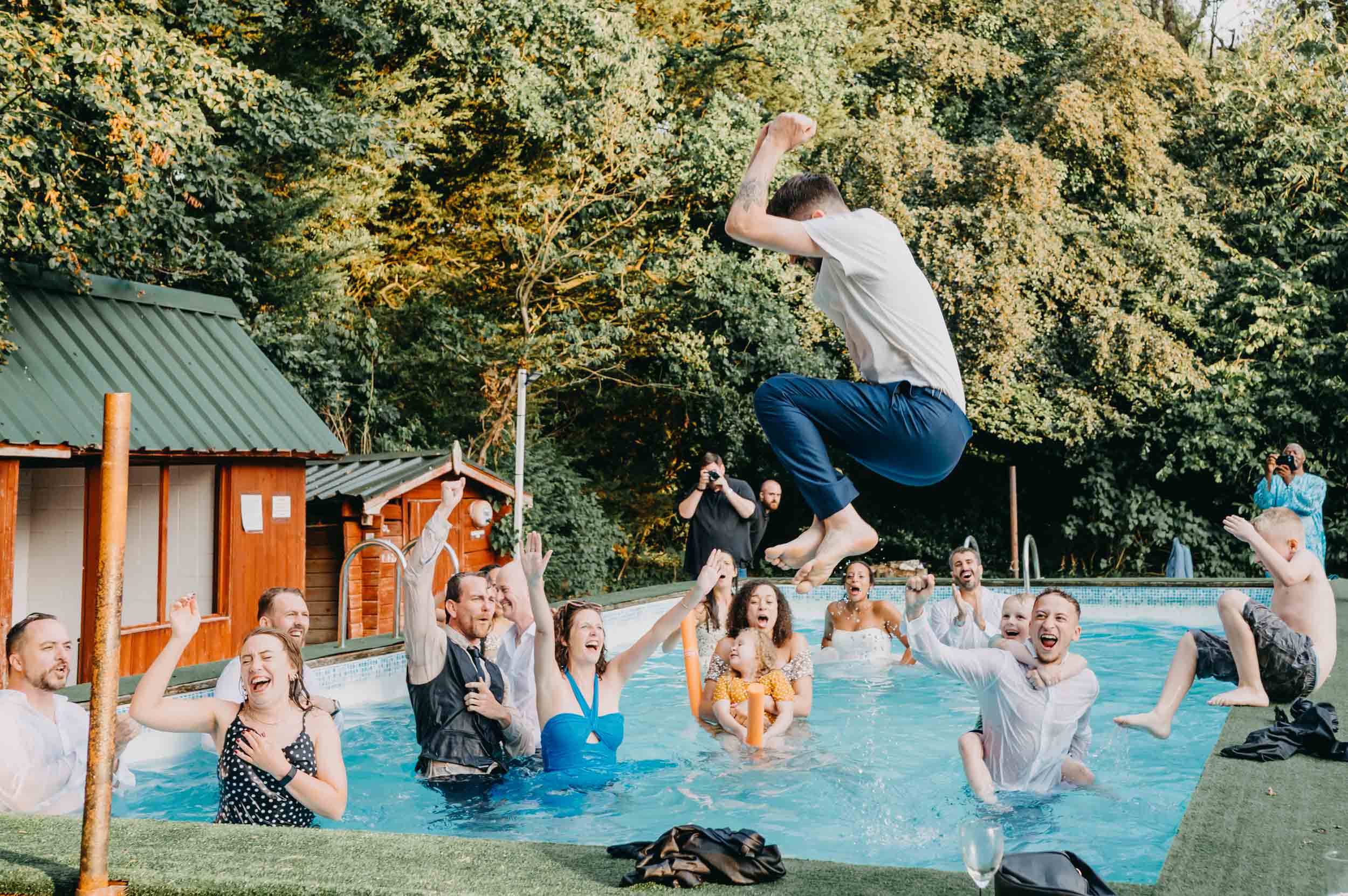 Unscripted wedding day moment as guests jump into the pool during the wedding party