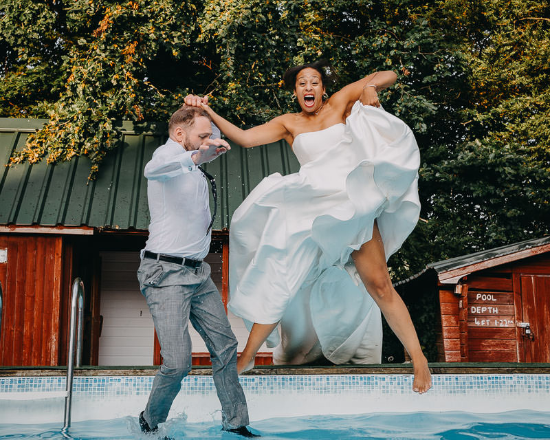 fun candid wedding moment in South Wales couple jumping into pool