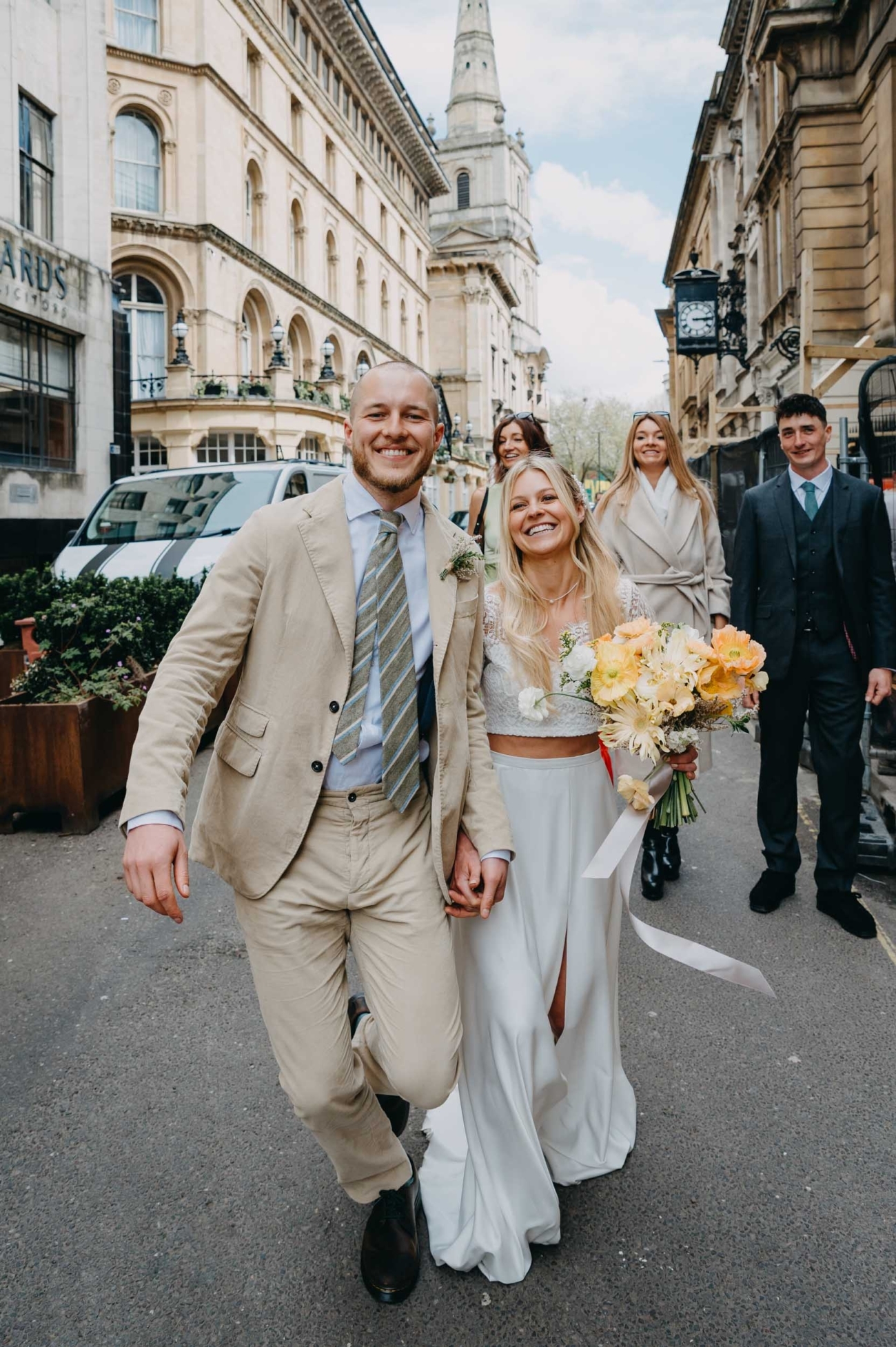 Candid wedding photography of a couple walking through Bristol city centre with guests captured by a Bristol wedding photographer
