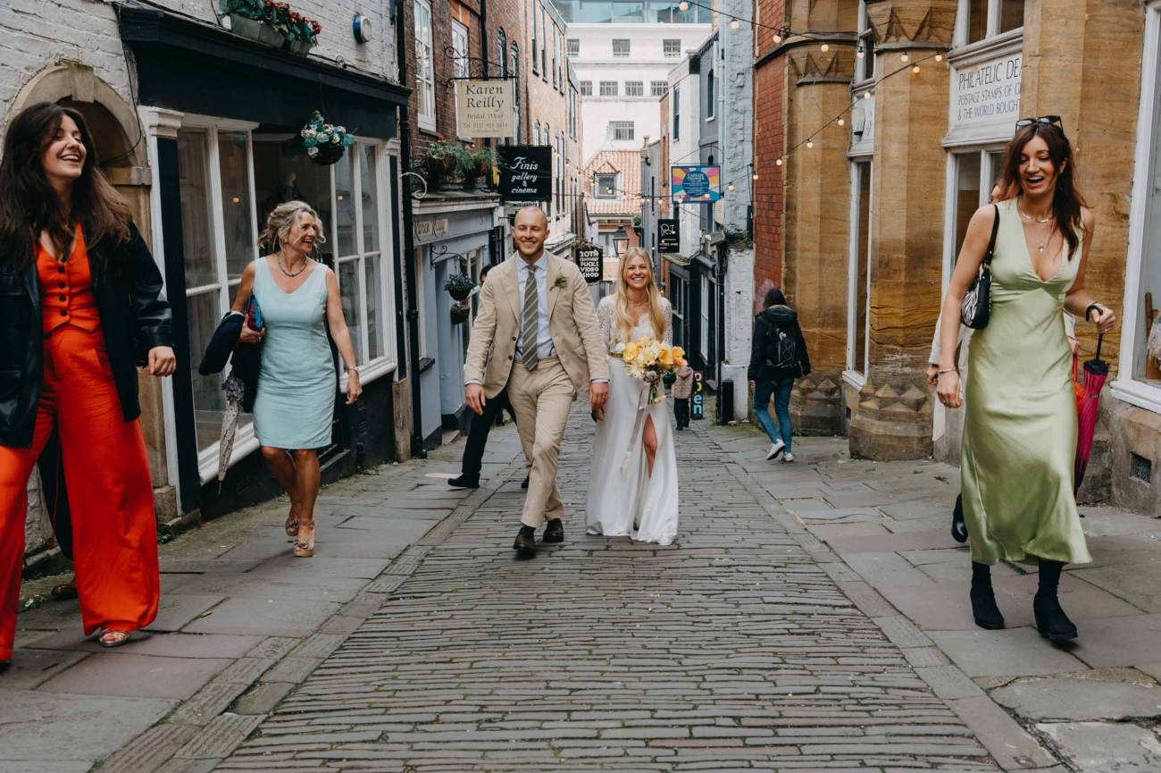 Documentary wedding photography of a couple walking with guests on Christmas Steps in central Bristol captured by a Bristol wedding photographer
