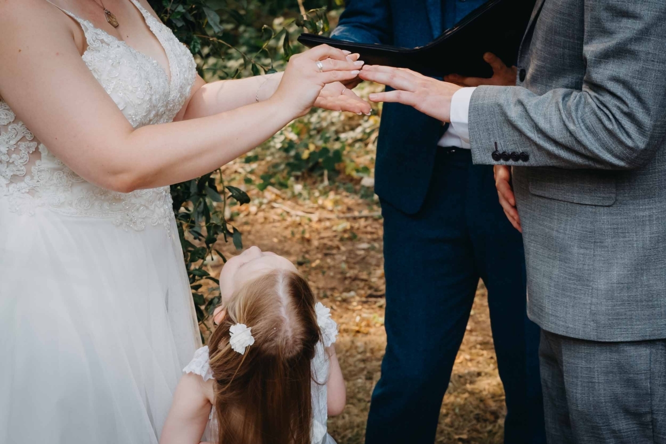 Documentary wedding photography in Bristol capturing the moment of exchanging rings during an outdoor ceremony with a child looking up