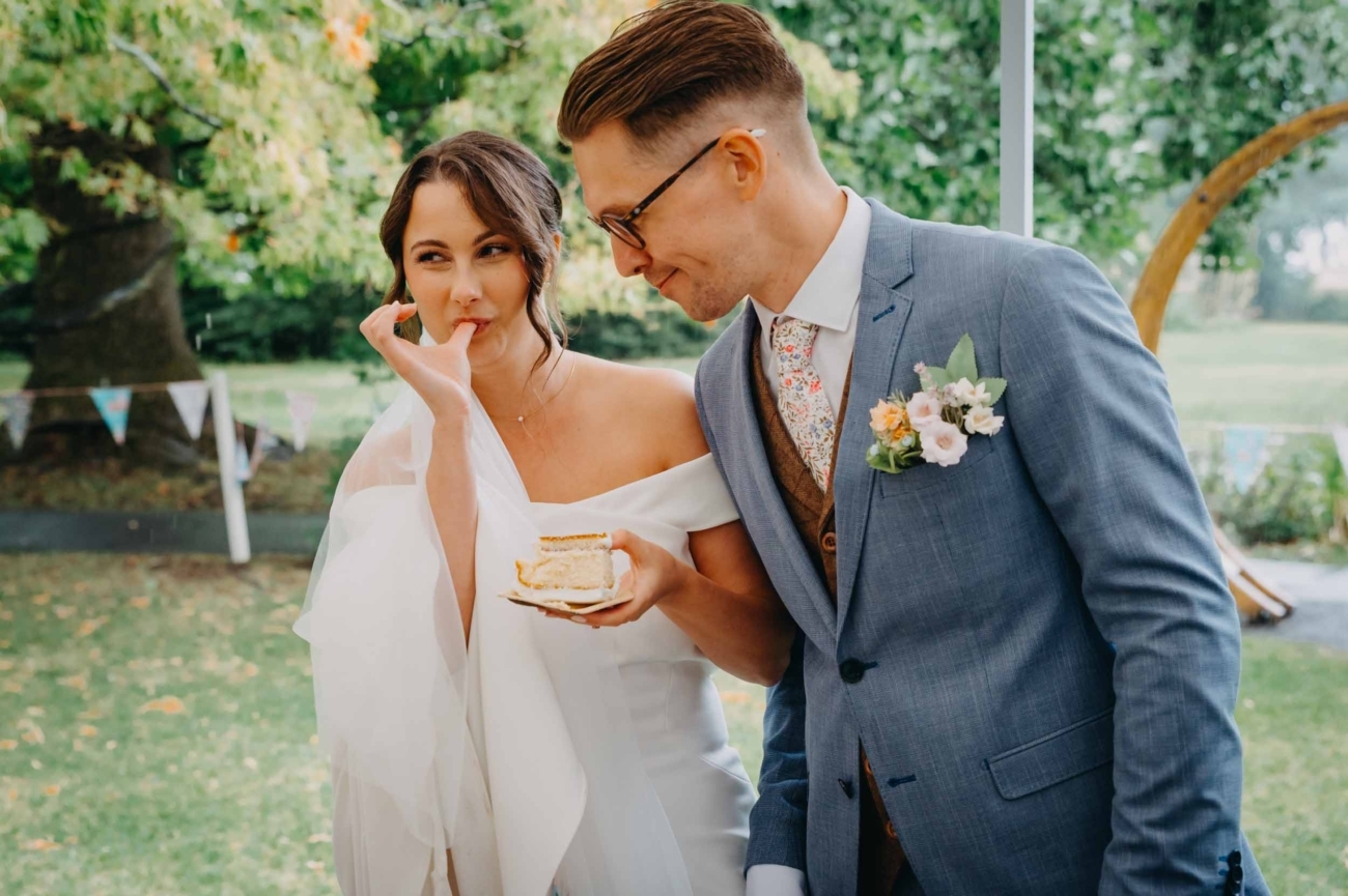 Candid wedding photography capturing a playful cake moment during an outdoor wedding reception by a Bristol wedding photographer