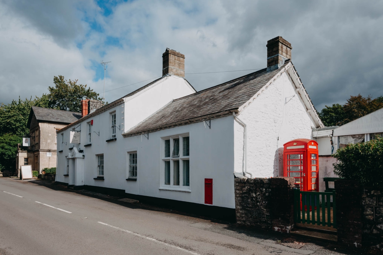 Old Post House wedding venue in St Fagans, Cardiff, with its white historic buildings and red telephone box