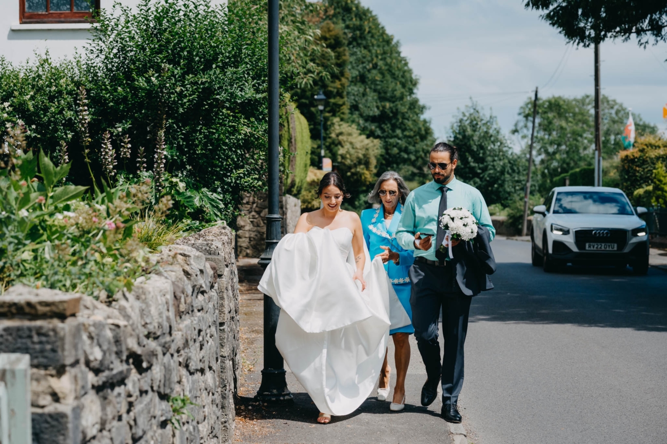 Bride walking along the street with family members on her way to the wedding ceremony at St Fagans