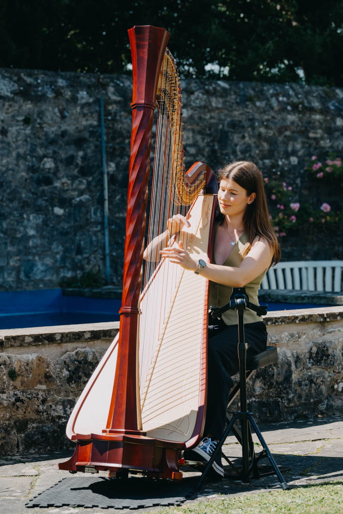 Harpist playing beside the pond before an outdoor wedding ceremony at St Fagans