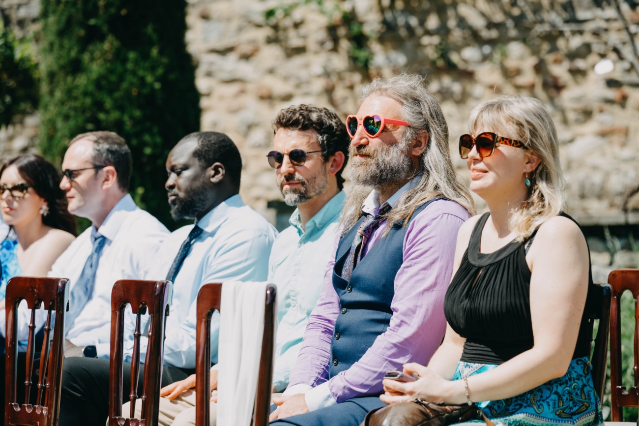 Wedding guests wearing colourful sunglasses while waiting for the ceremony to begin