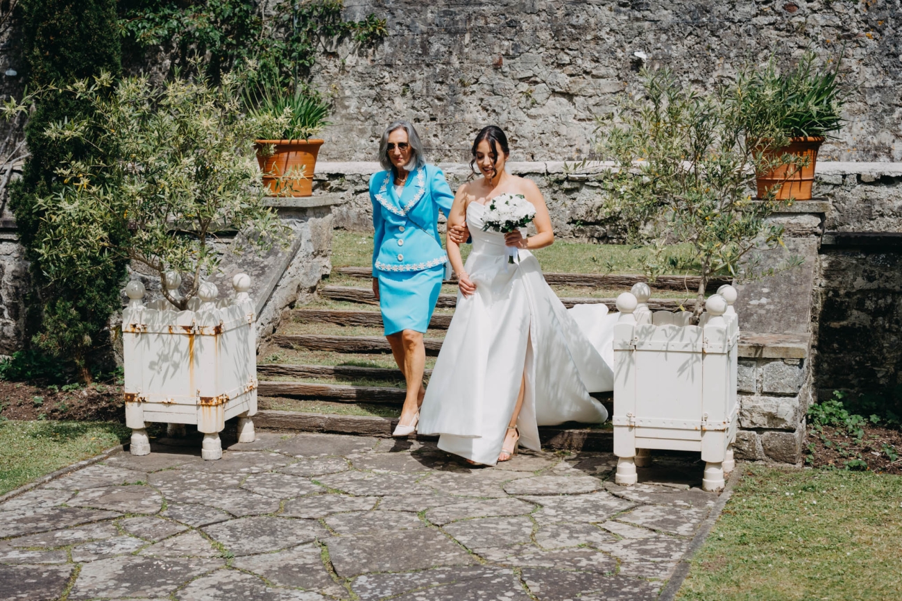 Bride descending the garden steps with a wedding guest on her way to the outdoor ceremony