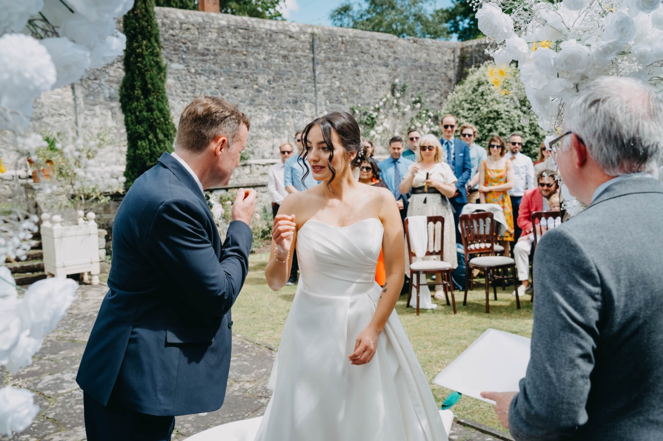 Bride and groom sharing a light-hearted moment with the celebrant during their outdoor ceremony at St Fagans