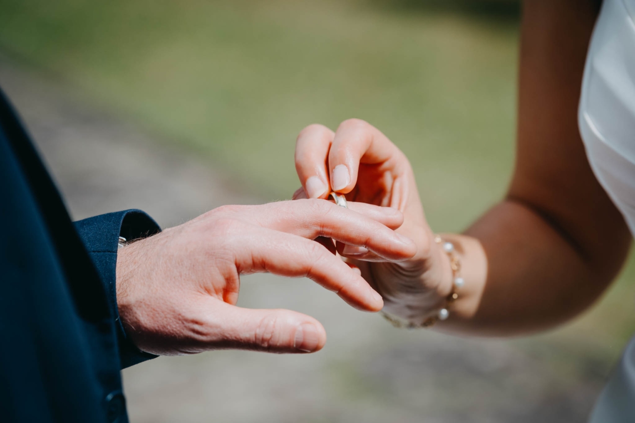 Close-up of the bride placing a wedding ring on the groom’s finger during the ceremony
