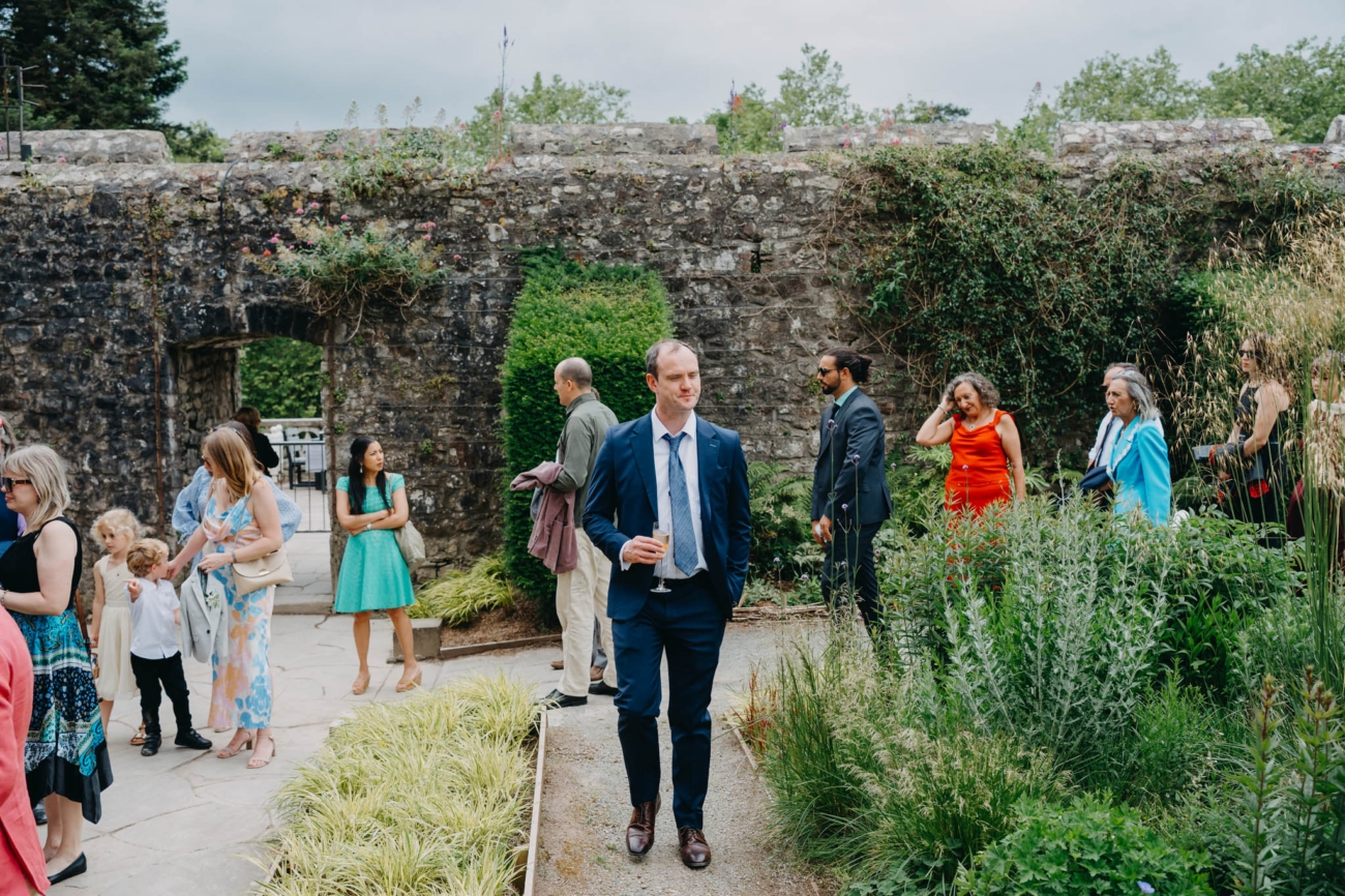 Wedding guest walking through the Italian Gardens with a glass of sparkling wine after the ceremony