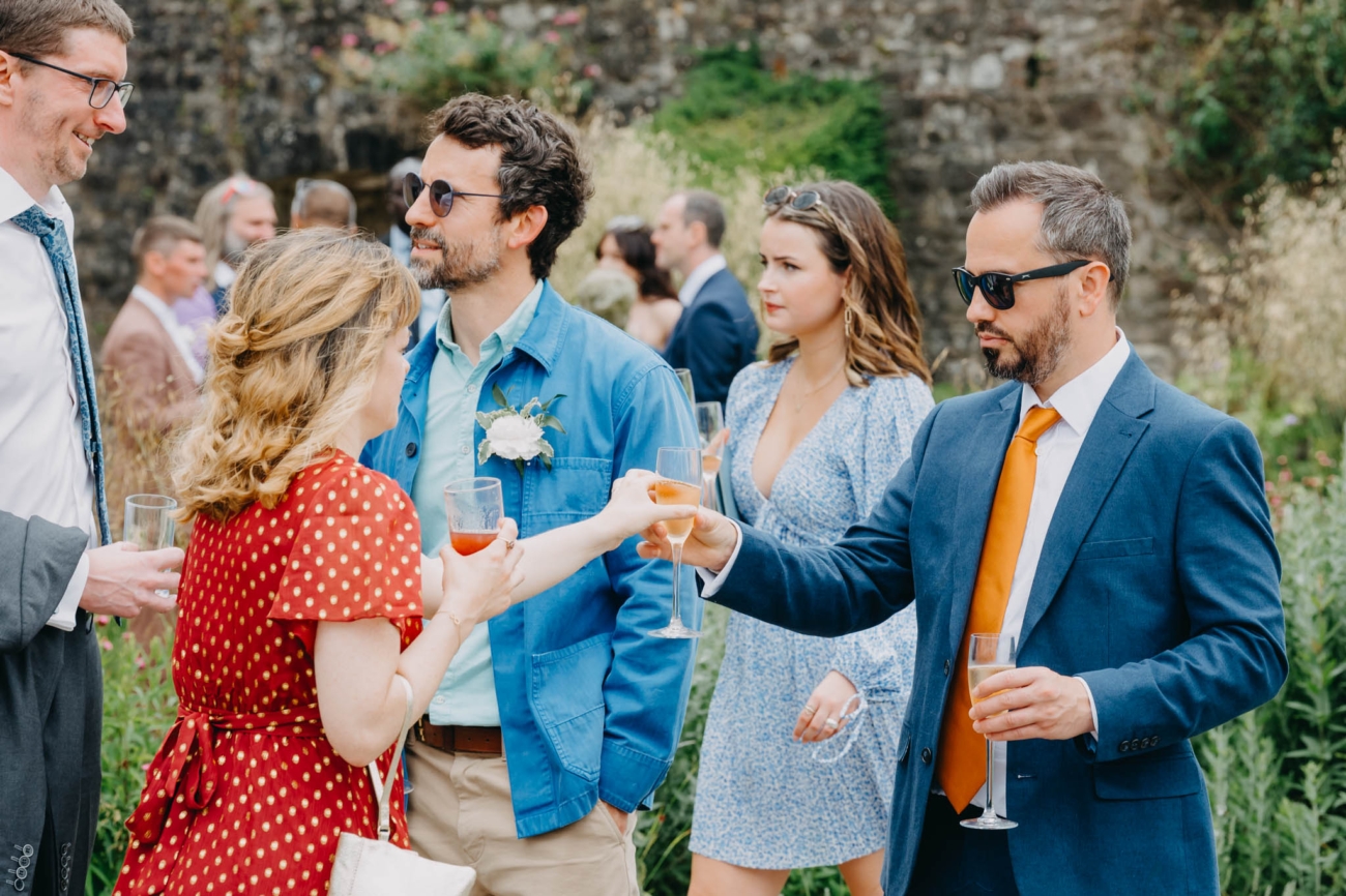Wedding guests clinking glasses during post-ceremony drinks in the Italian Gardens