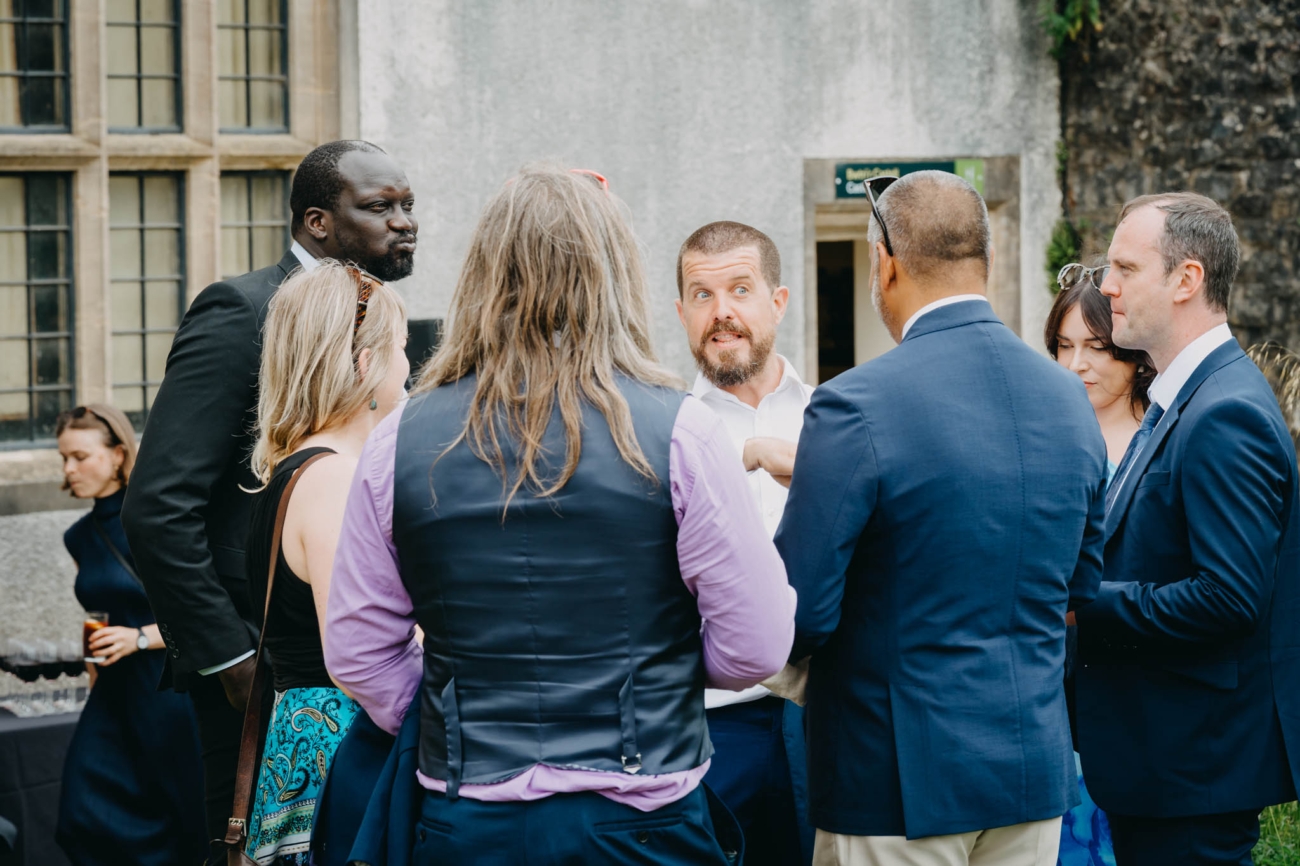 Group of wedding guests sharing an animated conversation after the ceremony at St Fagans