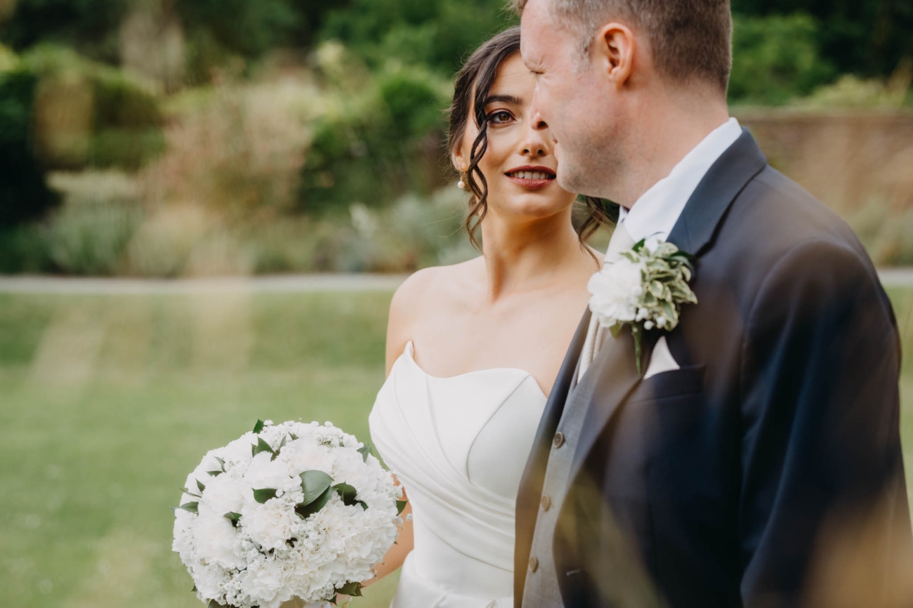 Bride looking at the groom during a close wedding portrait in the gardens at St Fagans