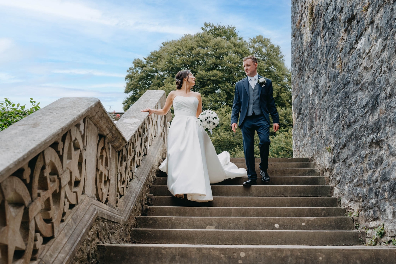 Newlyweds looking at each other as they walk down the stone steps at St Fagans National Museum of History