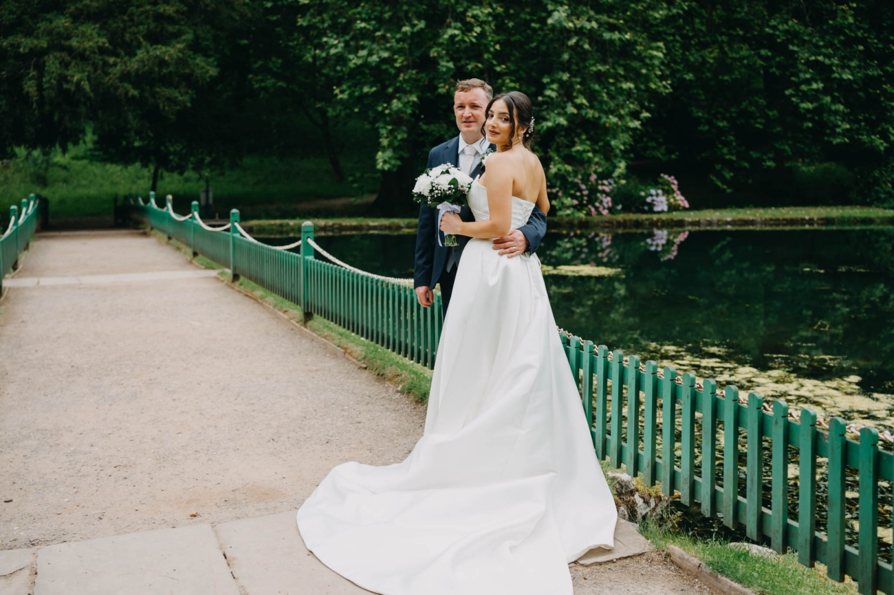 Bride and groom standing together beside the lily pond in the Italian Gardens at St Fagans