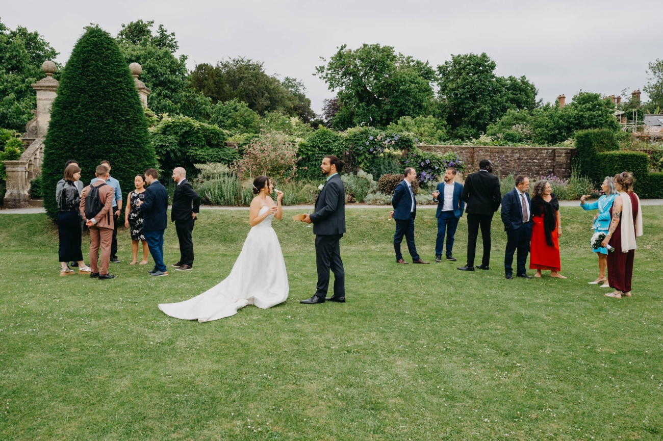 Bride and wedding guests talking in small groups on the lawn in the Italian Gardens